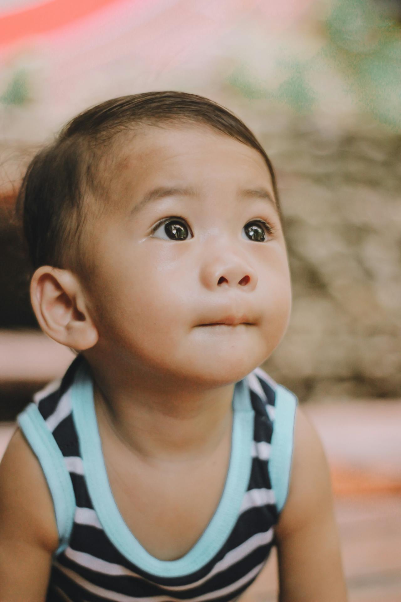 Small asian child on hands and knees, looking up inquisitively.